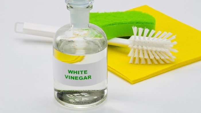 White vinegar in a glass bottle. White background. Organic cleaner.