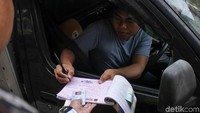 Seorang pelanggar menandatangani surat tilang.
