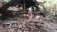 Beberapa warga mencari harta benda di reruntuhan bangunan.