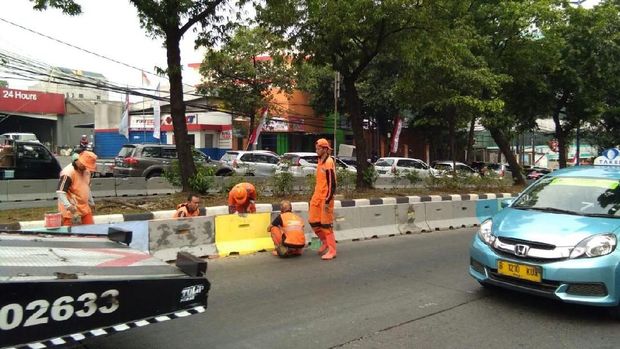 Petugas PPSU sedang mengembalikan warna separator yang sebelumnya dicat warna-warni