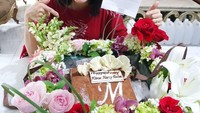Sebuah cake cokelat dengan inisial huruf M jadi hadiah untuk Merry di hari ulang tahunnya. Kue ini makin spesial karena dikelilingi bunga yang cantik. Foto: instagram @merryriana