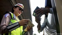 Seorang polwan sedang melakukan pengecekan STNK salah satu pengendara yang melanggar.