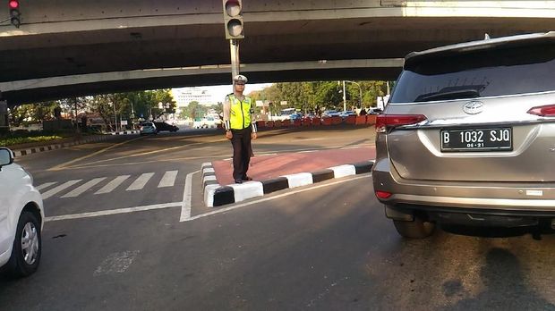 Polisi terlihat mengatur lalu lintas dan belum melakukan penidakan terhadap pengendara yang melanggar ganjil genap.