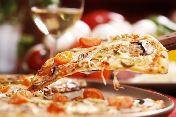 pizza italia Flatlay. Close-up of people hands taking slices of pepperoni pizza from wooden board. Table served with black textile napkin. Smartphone on table. People eat fast food in cafe.