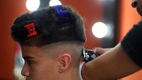 Saat Heredia sedang mencukur rambut salah seorang pelanggan di tokonya. Marcos Brindicci/Reuters.