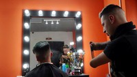 Heredia sedang mengambil gambar hasil potongan rambut pelanggannya menggunakan telepon genggam. Marcos Brindicci/Reuters.