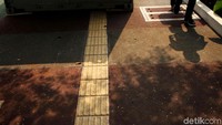 Seorang warga melintas di samping kontainer yang diletakkan di jalur khusus penyandang disabilitas.