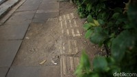 Balok-balok paving block terlihat pecah dan belum diperbaiki.
