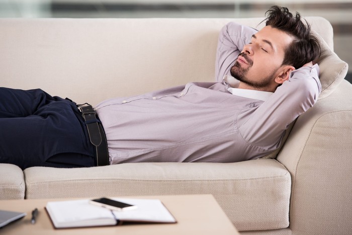 Tired businessman is sleeping on the sofa at the office.