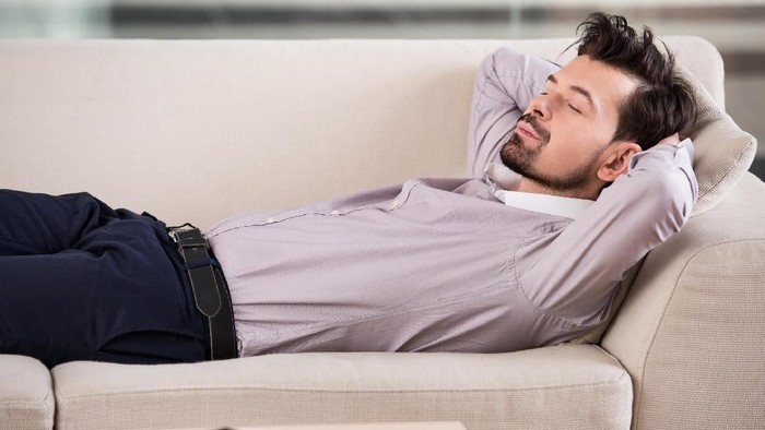 Tidur habis makan siang Tired businessman is sleeping on the sofa at the office.