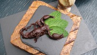 Siapa bilang kalajengking tidak bisa diolah jadi makanan manis? Di Archipelago, kalajengking yang mematikan, dilapisi dengan balutan cokelat dan daun mint yang segar untuk hidangan dessert. Foto: Archipelago London