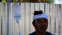 Seorang bapak diperban kepalanya karena tertimpa reruntuhan bangunan. REUTERS/Beawiharta.