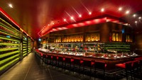 Begitu masuk, tertata meja panjang di bagian depan open kitchen. Lengkap dengan kursi bar merah yang mengelilinginya.Foto:  LAtelier de Joel Robuchon Bangkok  