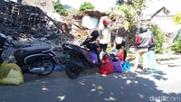 Warga mencoba mencari barang berharga yang bisa diselamatkan dari reruntuhan rumahnya.