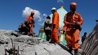 Para tim penyelamat bersama petugas kepolisian setempat menyisiri puing-puing bangunan untuk mencari korban selamat yang tertimbun runtuhan bangunan. Beawiharta/Reuters.