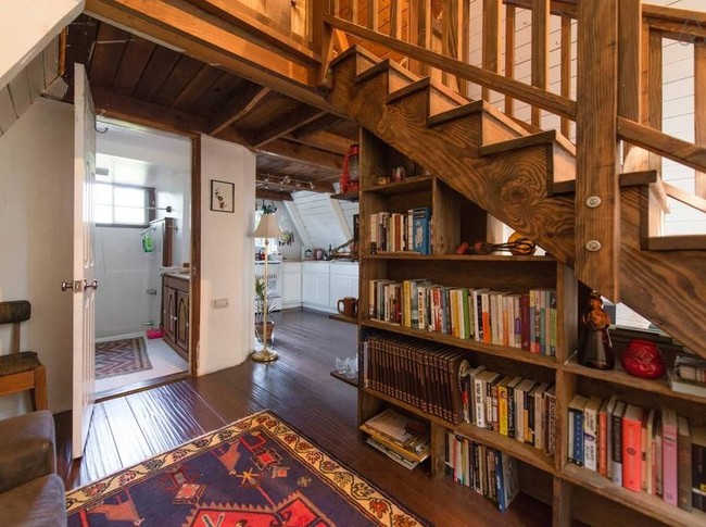 Bagian bawah tangga yang difungsikan sebagai perpustakaan kecil. Bisa jadi ide untuk menata rumah kamu sendiri, nih. Foto: Dok. Airbnb