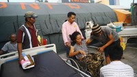 Seorang pasien dipindahkan menggunakan kursi roda.