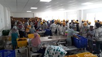 Para koki di kantin tenaga kerja lokal menggunakan seragam berwarna cream.