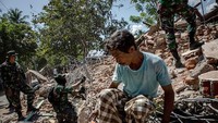 Bersama para penyelamat salah seorang warga menyisiri reruntuhan bangunan untuk mencari korban yang masih tertimbun puing-puing bangunan tersebut. Ulet Ifansasti/Getty Images.