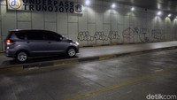 Mobil melintas di Underpas Trunojoyo yang dicoret-coret.