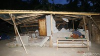 Seorang warga salat di rumahnya yang rusak berat akibat gempa.