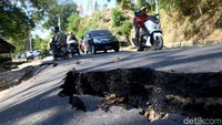 Pengendara melintas diantara jalan rusak.