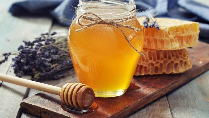 Madu Honey in jar with honey dipper on vintage wooden background