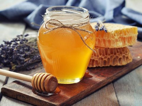 Honey in jar with honey dipper on vintage wooden background