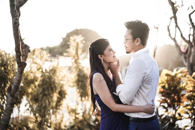 Denny dan Dita berfoto romantis dengan latar dedaunan yang disinari cahaya matahri. Tatapan Denny sambil memegang dagu Dita bisa membuat kamu yang melihat mereka ikut merasakan cinta keduanyanya. Foto: Instagram @matahatigraphy