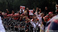 Para buruh meneriakan yel-yel dan menyanyikan lagu untuk membakar semangat.