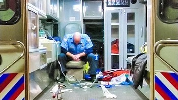 Staff medis ini tampak begitu lelah seharian bekerja, ia di dalam mobil ambulance yang terlihat berantakan. (Foto: Brightside)