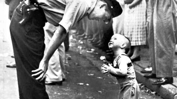 Seorang polisi dengan manis menghentikan bocah kecil dari persimpangan karena adanya sebuah parade, 1958. (Foto: Brightside)