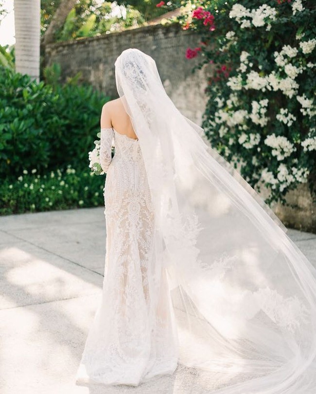 Veil tulle putih dengan panjang menyapu lantai memberi kesan dramatis bagi pengantin. Bagian veil pun diberi detail embroidery yang membuat look ini tampil mewah tanpa perlu banyak payet. Foto: Dok. Adrian Gan