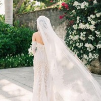 Veil tulle putih dengan panjang menyapu lantai memberi kesan dramatis bagi pengantin. Bagian veil pun diberi detail embroidery yang membuat look ini tampil mewah tanpa perlu banyak payet. Foto: Dok. Adrian Gan