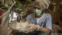 Salah seorang perajin sedang membuat sebuah mangkuk kayu.
