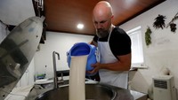 Alexey Dubovets menuangkan susu yang akan diolah menjadi keju. ilya Naymushin/Reuters.