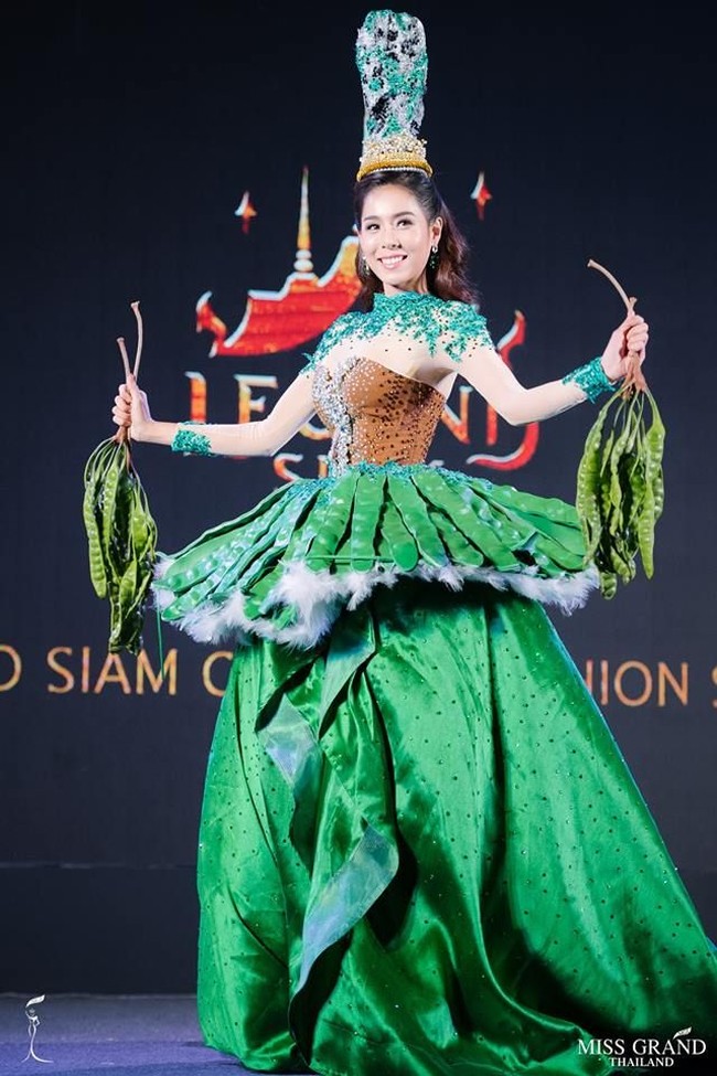 Inilah penampilan 2nd runner up Miss Grand Thailand 2018 Aink Ingchanok saat memakai kostum nasional di sela-sela jumpa pers pembukaan pusat rekreasi Legend Siam di Hotel Grand Hyatt, Bangkok, Thailand, 10 Agustus 2018. Aink memakai gaun yang bagian roknya dihiasi pete plastik. Dia pun tampak menenteng pete ke atas panggung.Foto: Facebook Miss Grand Thailand
