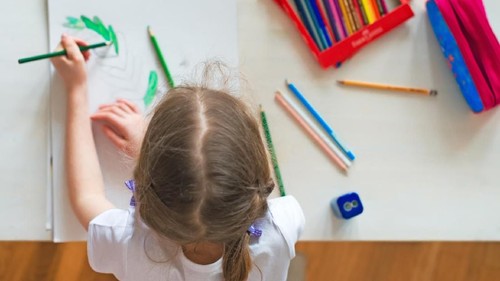 Little girl drawing with pencil at home. Top view.