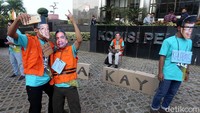Para peserta menggunakan topeng wajah para tersangka kasus korupsi saat melakukan aksi teatrikal.