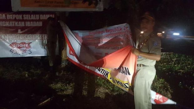 Satpol PP Depok saat menurunkan spanduk penolakan Neno Warisman di GDC
