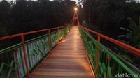 Penampakan jembatan di saat senja. Jembatan itu punya warna dominan oranye dan hijau.