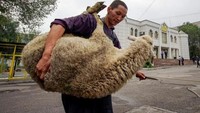 Seorang pria menggendong kambing untuk kurban di Lagos. Reuters.