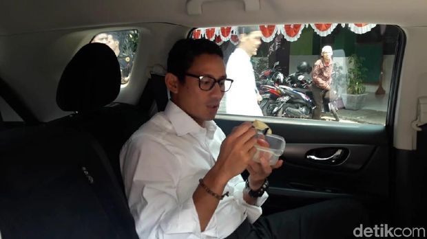 Sandiaga menyempatkan diri menyantap buah apel di dalam mobil