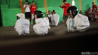 Bak pebalap, anak-anak mengikuti lomba balap karung dengan menggunakan helm.
