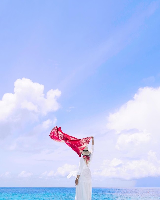 Berfoto di pantai Maldives, Dian Pelangi tampak elegan mengenakan dress berwarna putih. Ia mengenakan hijab motif bernuansa merah dan mengibarkan scarf bernuansa merah putih. (Foto: Instagram)