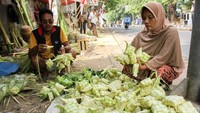 Seorang warga sedang memilih ketupat di salah satu lapak pedagang ketupat di Pasar Palmerah, Jakarta.