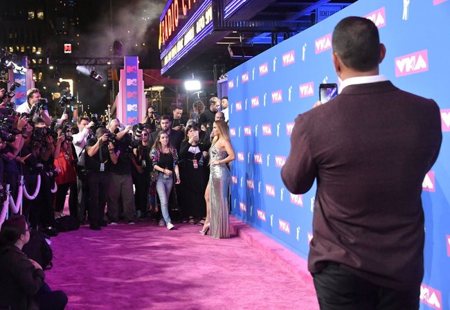 Ada momen menarik kala keduanya berada di red carpet. Sementara J.Lo berpose untuk fotografer, sang kekasih curi-curi kesempatan memotret pujaan hatinya itu dari kejauhan lewat kamera ponsel. Foto: Getty Images