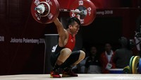 Deni mengangkat beban dengan posisi menekuk lutut.
