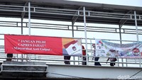 Spanduk itu berwarna dasar merah dengan tulisan putih Jangan Pilih Capres Jahat. Ada ilustrasi surat suara di bagian kanan spanduk.