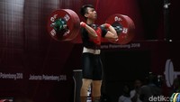 Deni berkonsentrasi untuk mengangkat beban dengan kedua tangannya.